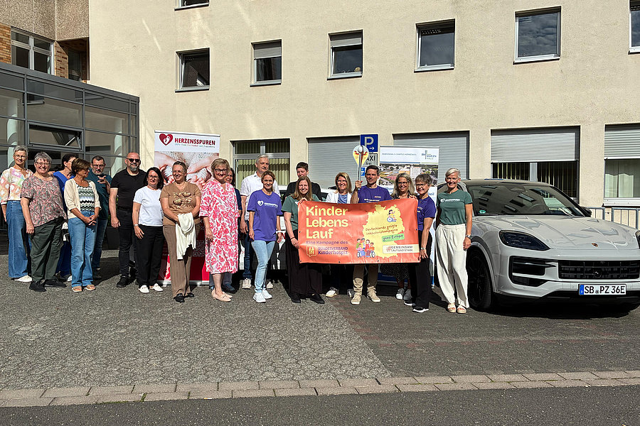 Gruppe von Menschen steht vor einem Gebäude und hält ein Banner mit der Aufschrift 'Kindes Lebens Lauf'