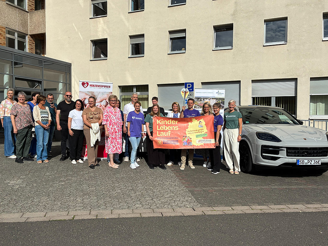Gruppe von Menschen steht vor einem Gebäude und hält ein Banner mit der Aufschrift 'Kindes Lebens Lauf'